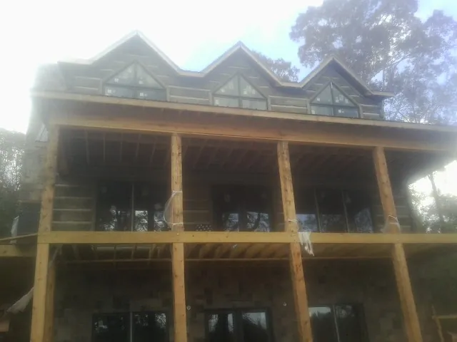Dormers and porch framing on a large log home under construction — Roof Coating work by our crew in Linwood