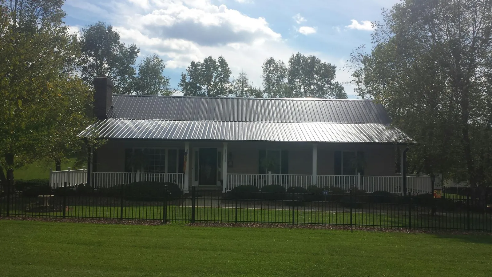 Gray metal roof on a brick ranch with a full width front porch — Gutter Guard Installation work by our crew in Linwood
